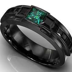 a black wedding band with a green stone in the center