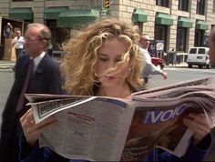 a woman reading a newspaper while standing next to a man