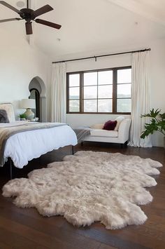 a bedroom with a bed, chair and rug on the floor in front of a window