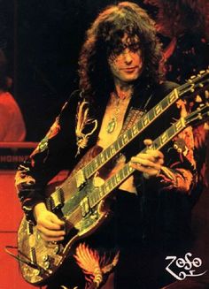 a man with long hair playing an electric guitar