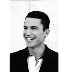 a black and white photo of a smiling man in a tuxedo jacket, with his eyes closed