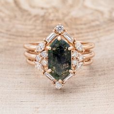 a fancy ring with a green stone surrounded by white and yellow diamonds on a wooden surface