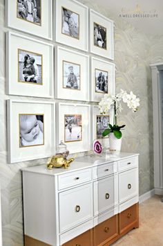 a white dresser topped with lots of drawers and pictures on the wall next to a vase filled with flowers