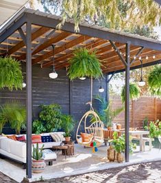 a man sitting on a swing chair in the middle of a patio with potted plants