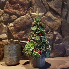 a potted christmas tree sitting next to a rock wall