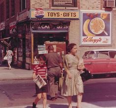 an old photo of people walking down the street in front of toys and gifts store