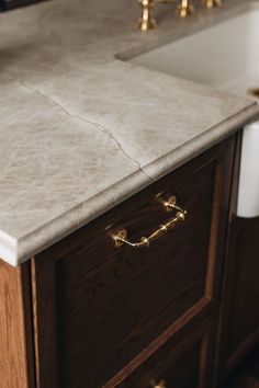 a bathroom vanity with marble top and brass handles