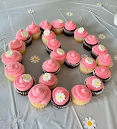 cupcakes with pink frosting and white flowers arranged in the shape of a circle