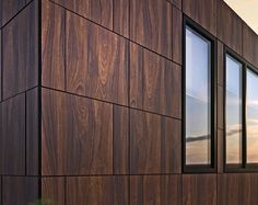 the side of a building with wood panels on it's sides and two windows