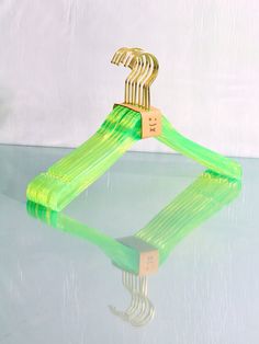 a green plastic hanger sitting on top of a glass table next to a white wall