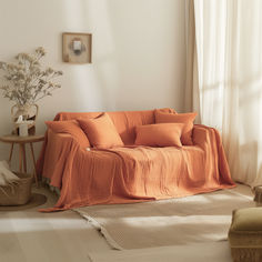 a living room with an orange couch and white curtains