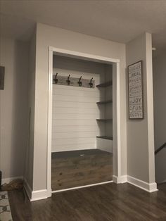 an empty room with some shelves on the wall and a coat rack in the corner