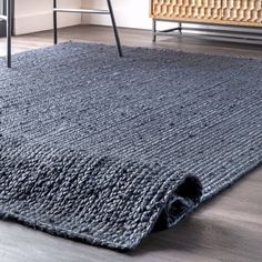 a gray rug on the floor with a chair and table in the backgroud