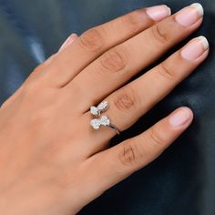 a woman's hand wearing a ring with two diamonds on it and one diamond in the middle