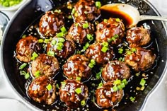 meatballs with sauce and green onions in a skillet