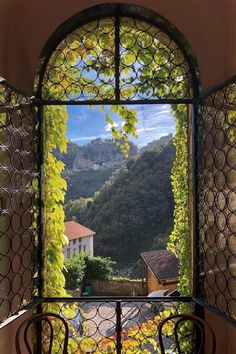 an open window with a view of the mountains and town below it, in front of some chairs