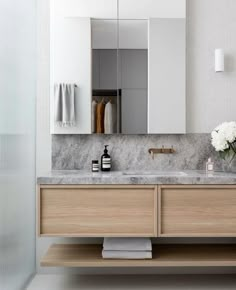 a bathroom vanity with marble counter top and wooden cabinetry, along with white flowers