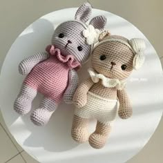 two crocheted stuffed animals sitting on top of a white table next to each other