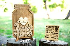 two wooden stumps with hearts on them and a sign that says guestbook & the frame was made from wood