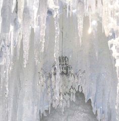 icicles hanging from the side of a building with light coming through them and snow on the ground