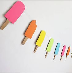 popsicles are lined up in different colors on a white background with clothes pins attached to them