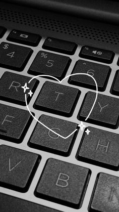 a heart is drawn on the keyboard of a black and white laptop computer, with stars around it