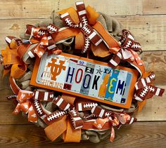 an orange and white football wreath with the word hok'em on it, decorated with bows