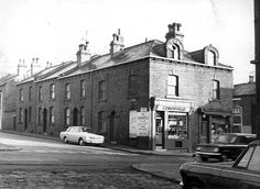 an old black and white photo of cars parked in front of buildings on a city street