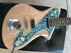 an electric guitar sitting on top of a black leather chair next to a blue carpet