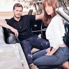 a man and woman sitting in the drivers seat of a car, posing for a photo