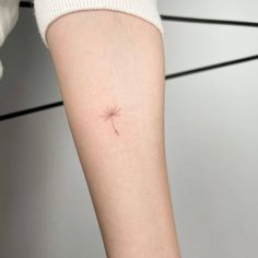 a small dandelion tattoo on the arm