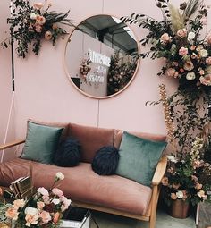 a living room filled with lots of furniture and flowers in front of a round mirror