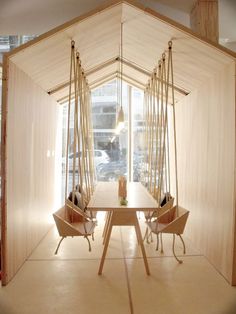 a room that has some chairs and a table inside of it with wooden poles hanging from the ceiling