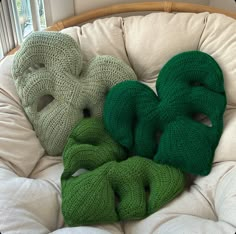 three knitted scarves sitting on top of a white chair next to a window