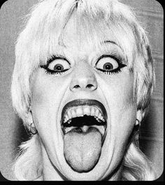 a black and white photo of a woman sticking her tongue out with an open mouth