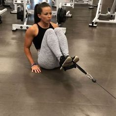 a woman sitting on the ground with her leg up and holding an object in front of her