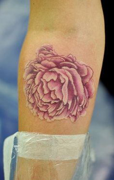 a pink flower tattoo on the left arm and leg, it looks like an image of a peonie