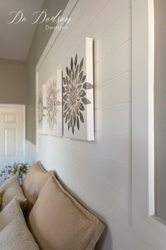 some pillows are sitting on the side of a wall near a vase with flowers in it