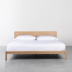 the bed is made up with white sheets and pillows, but no headboard or foot board