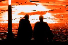 two people standing in front of an orange sky with birds flying over the city at sunset