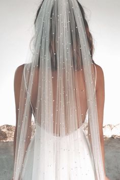 the back of a woman wearing a wedding veil with pearls on it's side