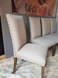 two beige chairs sitting next to each other in front of a painting on the wall