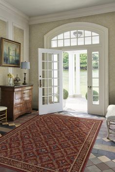 a large rug in the middle of a living room with french doors leading to an outside patio