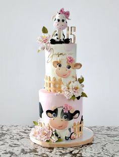 a three tiered cake decorated with farm animals and flowers on the top layer is pink, white, and gold