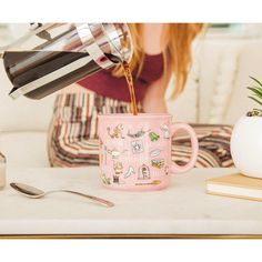 a woman pouring coffee into a pink mug