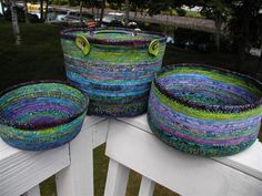 three woven baskets sitting on top of a white wooden bench next to grass and trees