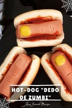 four hotdogs with ketchup and mustard on them are sitting on a black plate