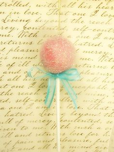 a pink lollipop sitting on top of a white stick with a blue bow