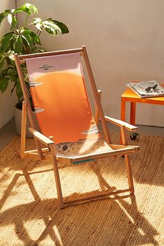 an orange chair sitting on top of a rug next to a potted plant