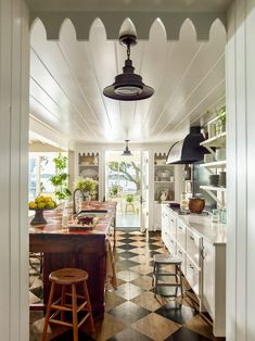 an open kitchen with checkered flooring and black pendant lights hanging from the ceiling